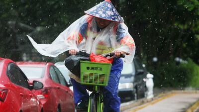 A Chinese sanitation worker rides a bicycle against the strong winds caused by Typhoon Hato on a road along the seacoast in Zhuhai, in China's southern Guangzhou province. AFP.