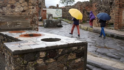 Tourists walk past a thermopolium, a commercial establishment where it was possible to purchase ready-to-eat food, inside the Pompeii archaeological site, southern Italy, Tuesday, Feb. 15, 2022. In a few horrible hours, Pompeii went from being a vibrant city to a dead one, smothered by a furious volcanic eruption in 79 AD. Then in this century, Pompeii appeared alarmingly on the precipice of a second death, assailed by decades of neglect, mismanagement and scanty systematic maintenance of heavily visited ruins. (AP Photo / Gregorio Borgia)