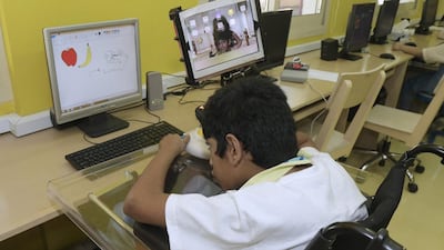 Harshil Shetty works using a specially adapted mouse on a computer at Al Noor Training Centre. Jeffrey E Biteng / The National