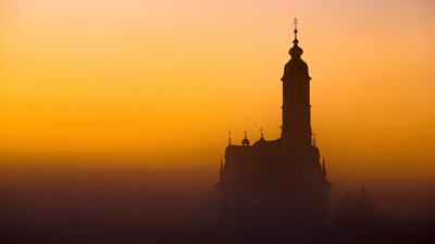 The Unserer Lieben Frau (Our Lady) pilgrimage church silhouettes against the sky painted in golden light as sun rises over Steinhausen, southern Germany. AFP
