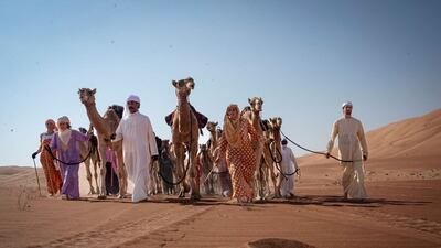 The group lead their camels across the dunes.