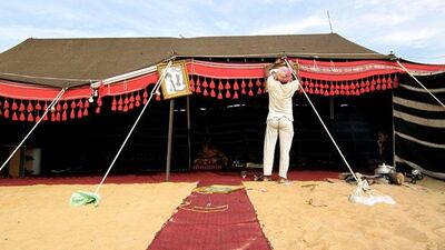 A man hangs photos of the late President Sheikh Zayed outside the tent of Fatima Al Hameli at Al Dhafra Festival in December 2012.