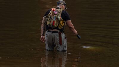 A search and recovery worker shines his flashlight through through murky waters near Camp Mystic, looking for remains of victims. AFP