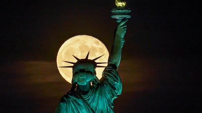 The Strawberry Supermoon rises in front of the Statue of Liberty in New York. AP