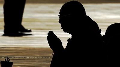 July 16, 2011: Tibetan spiritual leader the Dalai Lama (C) is silhouetted as he prays before blessing the Anacostia River in Washington with sand from a mandala mixed with water during a ceremony marking the end of the annual Kalachakra. AFP Photo / Jewe???