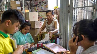 Aye Aye Nge handles a customer transaction from her stall at a new commercial building at the Shwe Mingalar market in Yangon. Insurance is a novelty in impoverished Myanmar where most people either can't afford to buy premiums or don't trust those selling them. Romeo Gacad / AFP