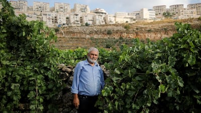 Palestinian man Mohammad Awad, 64, poses for a photo at his farm in the village of Wadi Fukin with the Jewish settlement of Beitar Illit in the background, in the Israeli-occupied West Bank, July 21, 2019. Reuters