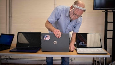 Damian Griffiths, director of Catbytes, a computer repair charity, checks and prepares donated computers for distribution at Ewart Community Hall in south London. AFP