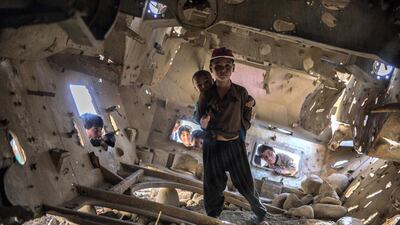 A boy stands inside an old tank in Qala-e-Naw, Badghis. Stefanie Glinski / The National