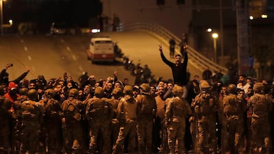Supporters of the Shiite Hezbollah and Amal Movement groups shout slogans as they stand in front of Lebanese army soldiers after a clash erupted between the anti-government protesters and them, in Beirut, Lebanon. AP Photo