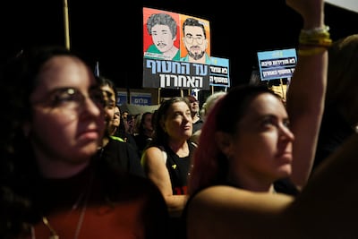 Protesters hold images of dead hostages Ran Gvili and Sudthisak Rinthalak at a rally in Tel Aviv. Reuters