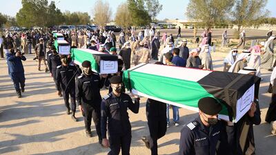 Relatives carry the coffins of eight Kuwaiti prisoners of war whose remains were found in a mass grave in Iraq, during a funeral procession in Kuwait City on January 13, 2021. AFP