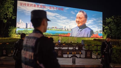Security personnel secure an area in front of a billboard featuring China's late paramount leader Deng Xiaoping on the 40th anniversary of China's "reform and opening up" policy. Nicolas Asfouri / AFP