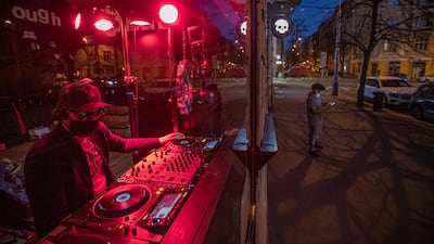 A DJ wearing protective face mask performs behind a window in Prague, Czech Republic. EPA