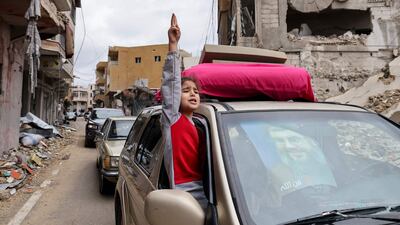 A girl gestures as she returns to her home in a car decorated with a portrait of Hezbollah's former leader Hassan Nasrallah. AFP