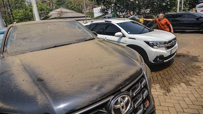 A man clears volcanic ash from his car following the eruption, which produced a fountain of lava and booming sounds that could be heard up to 700km away. AFP