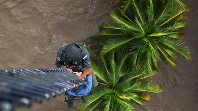 A member of the Honduran Air Force hangs from a ladder from a helicopter as he rescues a man following the overflowing of the Chamelecon river after the passage of Hurricane Iota, in the municipality of Choloma, department of Cortes, Honduras. AFP