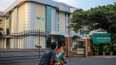 A cyclist rides past the Serum Institute of India's Hadapsar plant in Pune, Maharashtra. The institute will deliver 220 million doses over the next few months that can cover 8 per cent of the country's population. Bloomberg