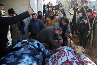 Mourners stand next to bodies of people killed in an air strike in Idlib, Syria, on December 26. EPA