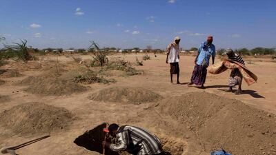 July 12, 2011: Osman Ali Aliyow Mursal digs a burial plot amongst other recent graves for his four-year-old son Aden Ibrahim, as men prepare to pray over the boy's body, wrapped in a plastic mat, on the outskirts of Ifo II Camp, outside Dadaab, Kenya. (A???