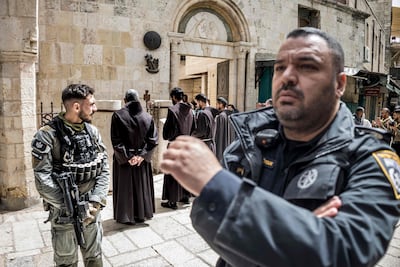 An Israeli policeman walks past a border guard as a group of Franciscan friars takes part in the Good Friday procession along the Via Dolorosa in the old city of Jerusalem on April 3, 2026. AFP