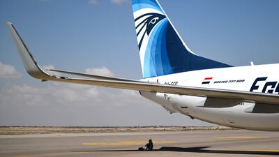 A visitor sits under the shadow projected by a plane during the Egypt International Air Show, at El Alamein International Airport. EPA