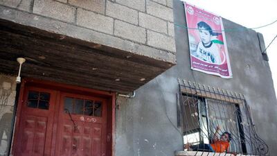 Malak Basioni sits in the window of her family’s home underneath a giant poster of her brother, Fares, who was killed by shrapnel as he slept when an Israeli air strike hit a field nearby the family home last November in Beit Hanoun.