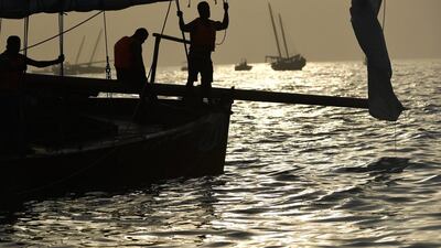 Sailors aboard a dhow called Al Qumzi (No. 141) wait during sunrise for the start of the race. Martin Dokoupil / EPA