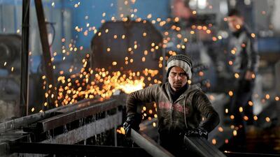 An India worker arranges steel tubes at a factory in the Muwaqer Industrial Estate, northern Jordan. A new trade deal with Europe, a rush of foreign investment and ambitious public works are to put 200,000 Syrian refugees to work in the country. Raad Adayleh/AP Photo
