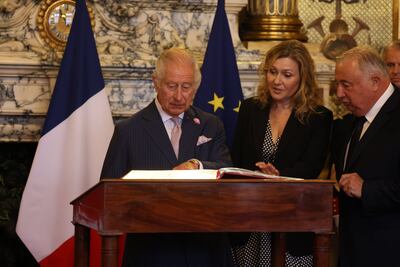 King Charles III, watched by president of the Senate Gerard Larcher and president of the National Assembly Yael Braun-Pivet, signs the visitors book in the Salle des Conferences. PA