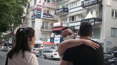 A man wearing a face mask to protect against the spread of coronavirus, embraces a friend in city the centre, in Ankara, Turkey. AP Photo