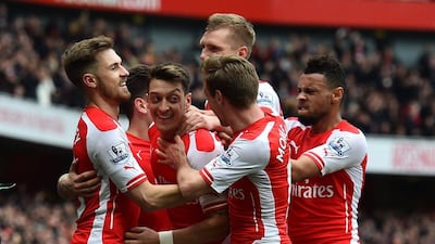 Arsenal players mob Mesut Ozil after his stunning free-kick put Arsenal 2-0 ahead against Liverpool. Ben Stansall / AFP