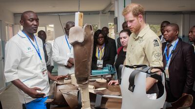Prince Harry examines a prosthetic. EPA