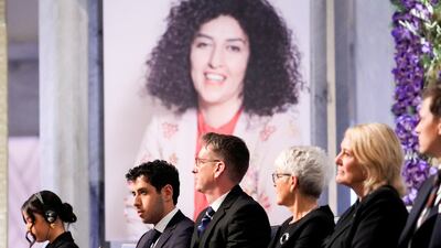 Narges Mohammadi's children Kiana Rahmani, left, and Ali, second left, sit before a portrait of their mother at the Nobel awards ceremony in Oslo. Reuters