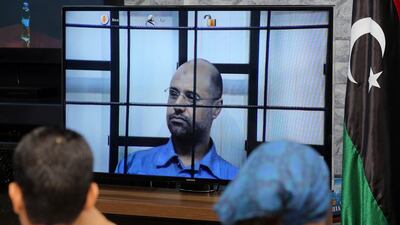 Journalists watch as unseen judges question Saif Al Islam (C) as he is broadcasted live from the western Libyan city of Zintan, from inside a room in Tripoli on April 27, 2014. Mahmud Turkia / AFP