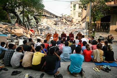 People attend a memorial service near the rubble of a collapsed building in Mandalay on April 3, six days after a 7. 7-magnitude earthquake struck central Myanmar. AFP