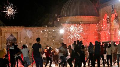 Palestinian protesters react as stun grenades fired by Israeli security forces explode in the air, during clashes at the Al Aqsa Mosque compound in Jerusalem. AFP
