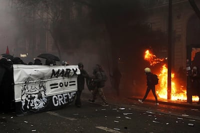 epa08046785 Protesters protect themselves behind a banner reading 'Marx or Die' as they throw projectiles during a demonstration against pension reforms Paris, France, 05 December 2019. Unions representing railway and transport workers and many others in the public sector have called for a general strike and demonstration to protest against French government's reform of the pension system. EPA/YOAN VALAT