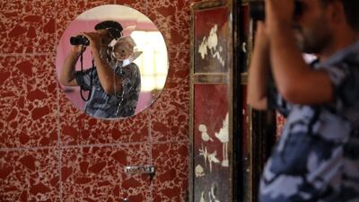 A reflection in a mirror shows an Iraqi Sunni gunman monitoring with binoculars as he secures an area in Dhuluiya, some 75 kms north of Baghdad after security forces and allied tribesmen retook the city from Islamic States (IS) fighters. Ahmad Al Rubaye / AFP