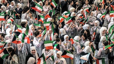 Secondary school students wave the Kuwaiti flag as they gather in the grounds of the Fajr al-Sabah School to attend in-person classes in Kuwait City on May 3, 2026. High school students resumed in-person classes after a suspension of more than two months following military strikes launched by the US and Israel against Iran that killed its supreme leader, triggering a war that spread across the Middle East and prompting the Kuwaiti Education Ministry to implement remote learning for students. (Photo by YASSER AL-ZAYYAT / AFP) /