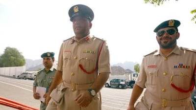 Lt Col Bader Al Tunaji, centre, the director of Hatta police station, enters his office.