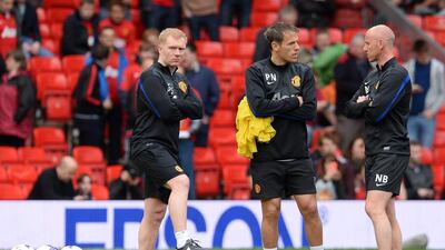 Manchester United's coaching team Paul Scholes, left, Phil Neville, centre, and Nicky Butt are pictured before the start of the English Premier League football match between Manchester United and Norwich City at Old Trafford in Manchester, northwest England, on April 26, 2014. AFP PHOTO/ANDREW YATES
