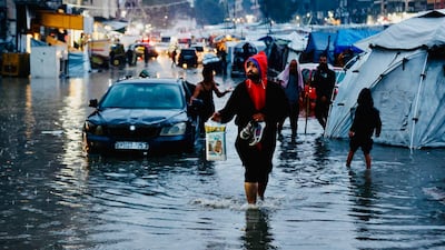 Displaced Palestinians walk through floodwater after heavy rain in Gaza city. AFP