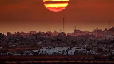 The sun setting behind destroyed buildings in Gaza. AFP
