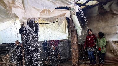 A Palestinian man pokes the nylon sheets covering the roof of his tent to remove the accumulating rain water, as children watch, on a rainy day in al-Amal (hope in Arabic) neighbourhood of Beit Lahia in the northern Gaza Strip. AFP