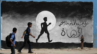 Two Palestinian schoolboys walk past graffiti painted on a wall of the United Nations school of Beit Hanun, in the northern Gaza Strip. Thomas Coex / AFP