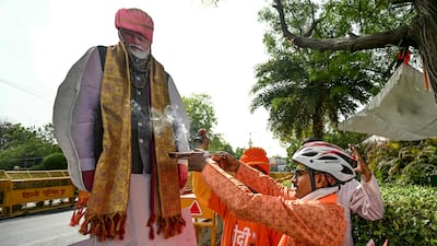A supporter of Prime Minister Narendra Modi performs rituals next to a cut-out of the BJP leader outside the party's headquarters in New Delhi. AFP
