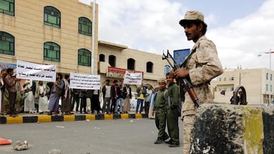 A Yemeni soldier keeps watch as Baha'i Faith members hold banners during a protest against the trial of member of the Baha'i Faith Hamed Haydara, in 2016. EPA