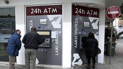 Cypriots withdraw money from ATMs outside a closed branch of Laiki Bank in Nicosia. Petros Giannakouris / AP Photo