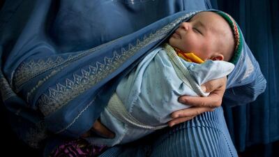 An Afghan woman holds her newly born baby wrapped in her burqa.